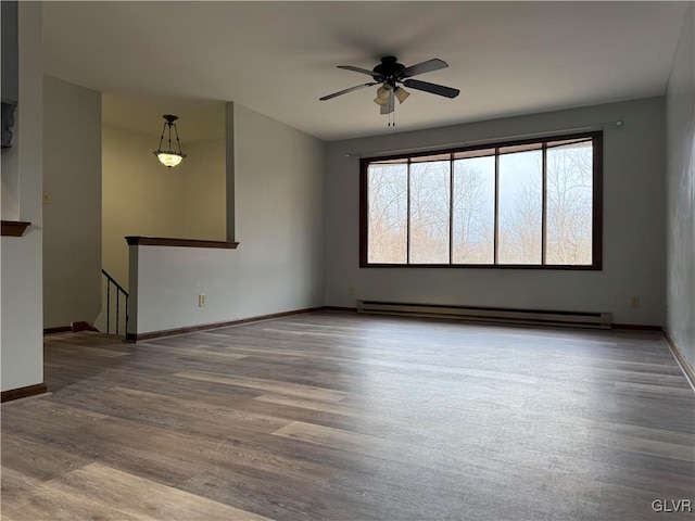 unfurnished room with hardwood / wood-style flooring, baseboard heating, a healthy amount of sunlight, and ceiling fan