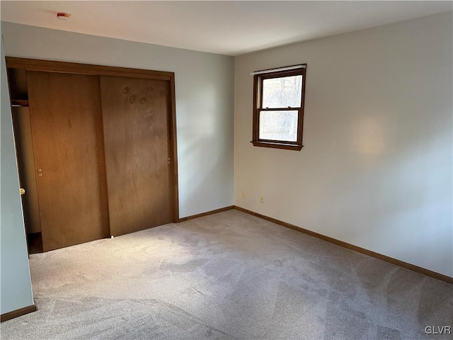 unfurnished bedroom featuring light colored carpet and a closet