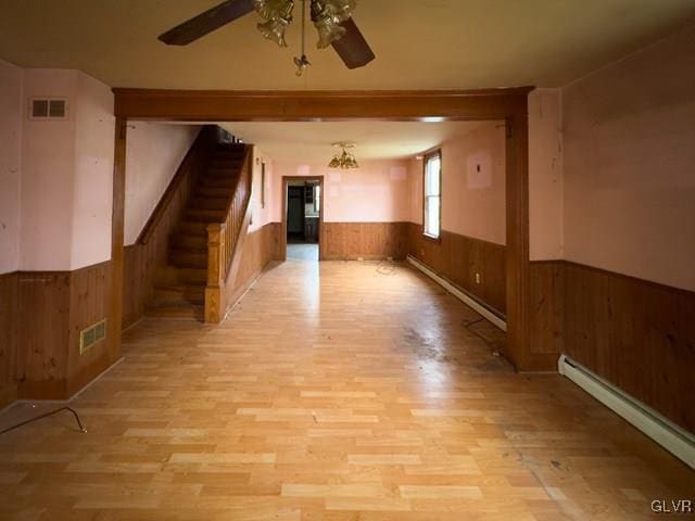 empty room featuring baseboard heating, ceiling fan, and light hardwood / wood-style floors