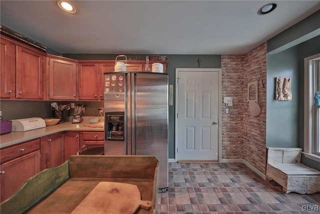 kitchen with stainless steel fridge and brick wall