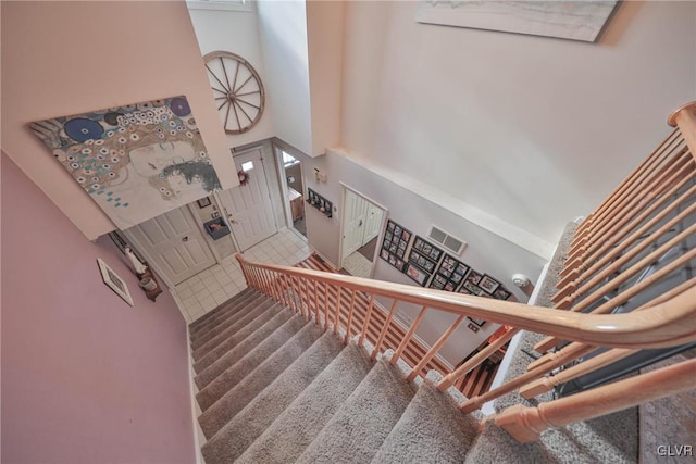 staircase with carpet flooring and a high ceiling