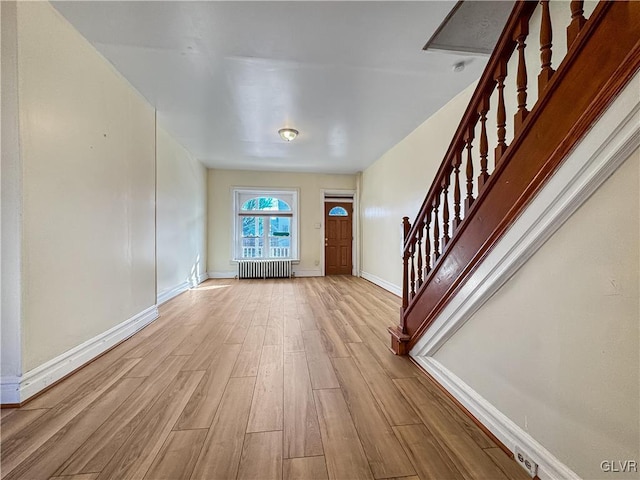 entryway with light hardwood / wood-style floors and radiator heating unit