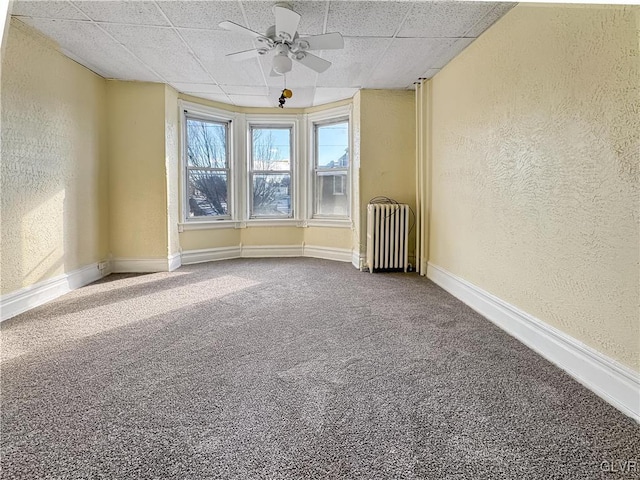 carpeted empty room with ceiling fan and radiator