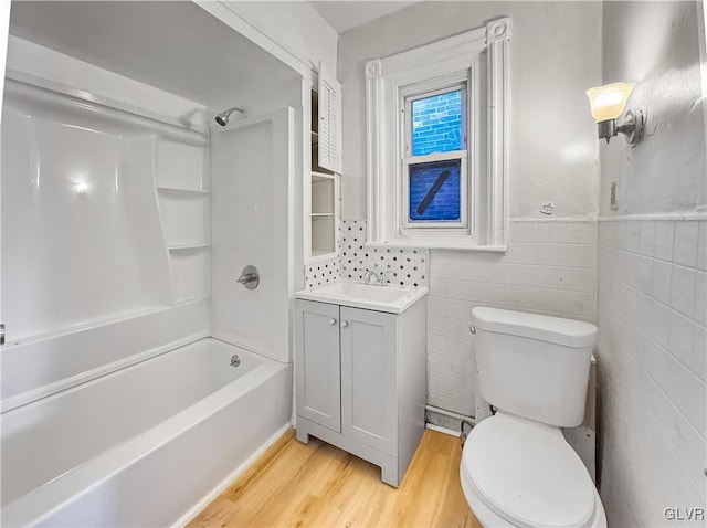 full bathroom with vanity, shower / washtub combination, hardwood / wood-style flooring, tile walls, and toilet