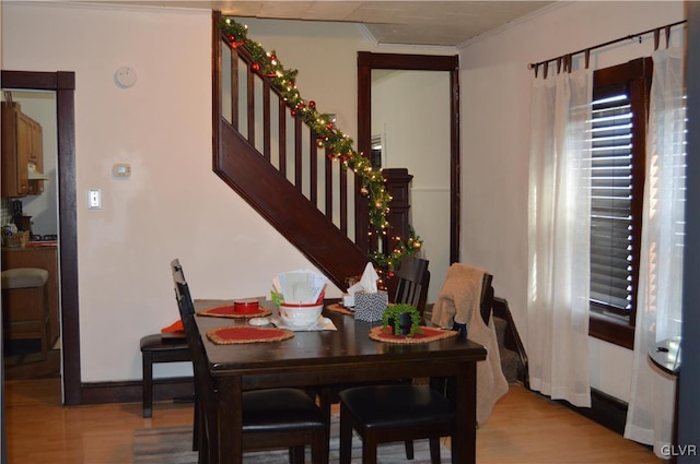 dining area with light wood-type flooring and ornamental molding