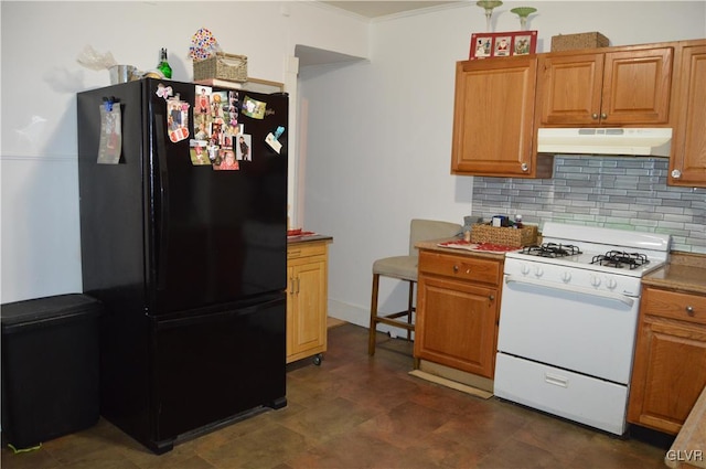 kitchen featuring white range with gas stovetop, decorative backsplash, black fridge, and ornamental molding