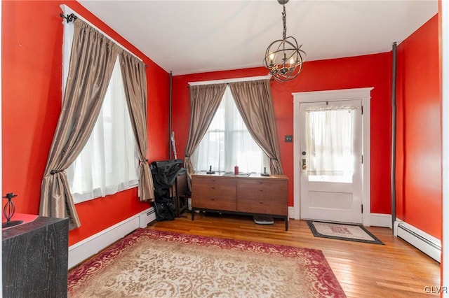 entryway featuring hardwood / wood-style flooring, a chandelier, and a baseboard heating unit