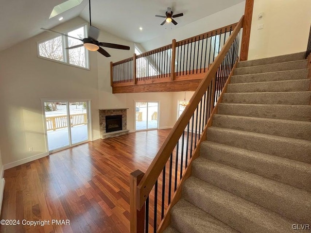 unfurnished living room featuring ceiling fan, a fireplace, high vaulted ceiling, and hardwood / wood-style flooring