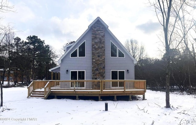 snow covered back of property featuring a deck