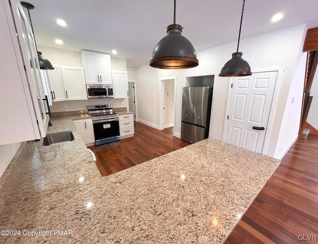 kitchen with kitchen peninsula, appliances with stainless steel finishes, light stone counters, pendant lighting, and white cabinets