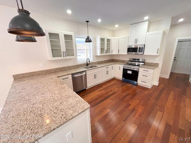 kitchen with white cabinets, decorative light fixtures, light stone countertops, and stainless steel appliances