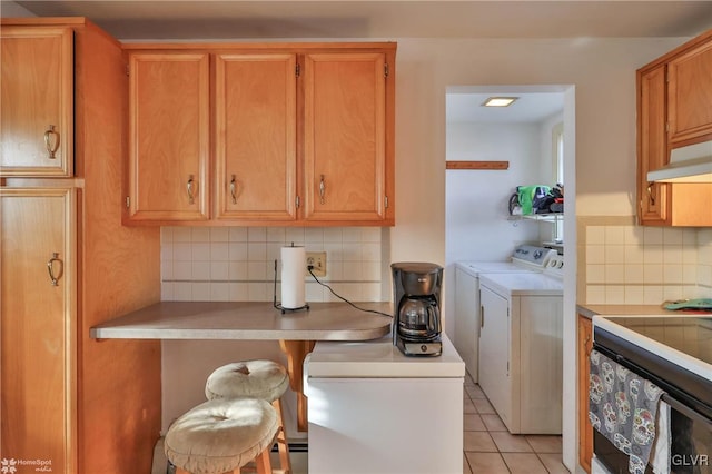 laundry room with washer and clothes dryer and light tile patterned floors