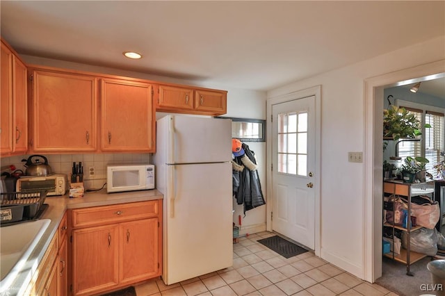 kitchen featuring backsplash, sink, a healthy amount of sunlight, and white appliances