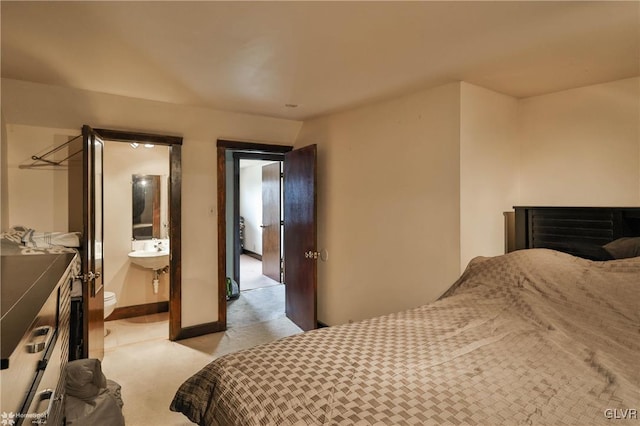 carpeted bedroom featuring sink and connected bathroom