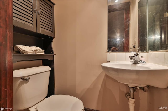 bathroom featuring backsplash, sink, and toilet