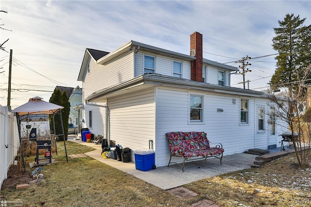 back of property featuring a gazebo, a patio area, and a lawn