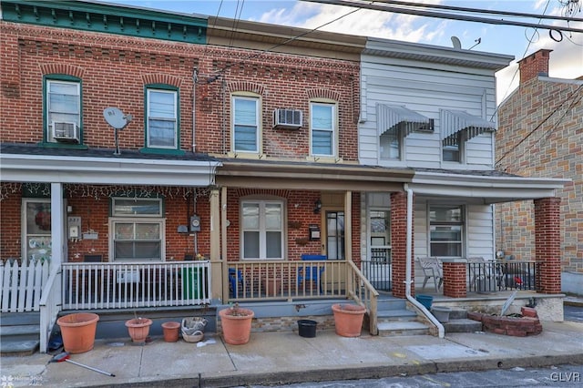 townhome / multi-family property featuring an AC wall unit, cooling unit, and a porch