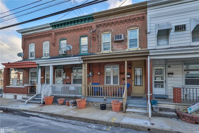 townhome / multi-family property featuring covered porch and a wall unit AC