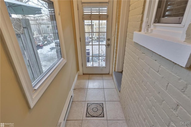 entryway featuring plenty of natural light, light tile patterned flooring, brick wall, and a baseboard heating unit