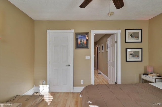 bedroom featuring ceiling fan, light hardwood / wood-style floors, and a textured ceiling