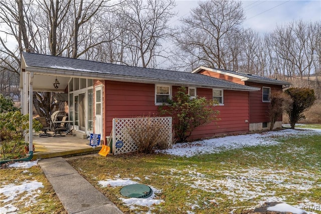 snow covered rear of property featuring a patio area and a yard