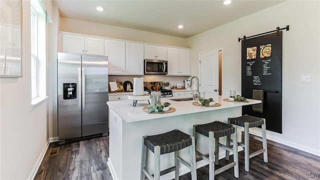 kitchen with white cabinets, stainless steel appliances, and a center island with sink