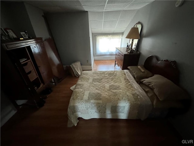 bedroom featuring a drop ceiling and hardwood / wood-style floors