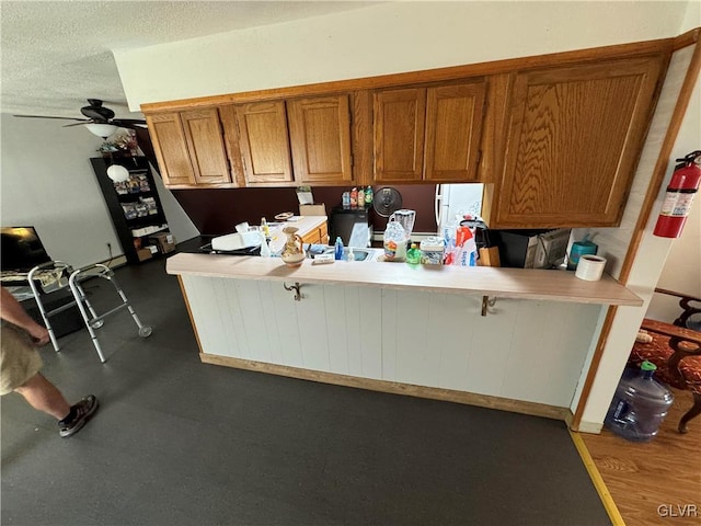 kitchen with ceiling fan, kitchen peninsula, and a textured ceiling