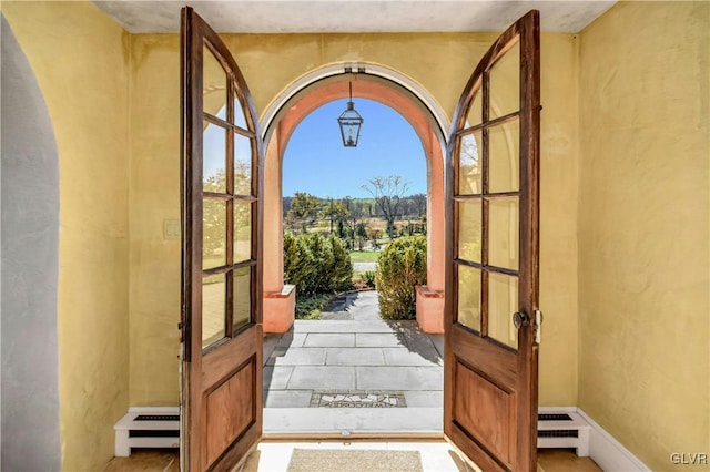 doorway with french doors, light tile patterned floors, and a baseboard radiator