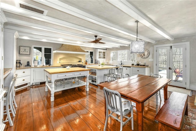 dining area featuring beamed ceiling, ceiling fan, wood-type flooring, and french doors