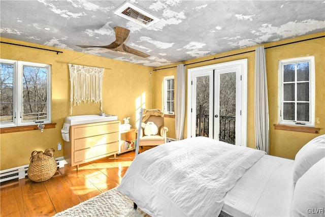 bedroom with french doors, access to outside, ceiling fan, a baseboard radiator, and hardwood / wood-style floors