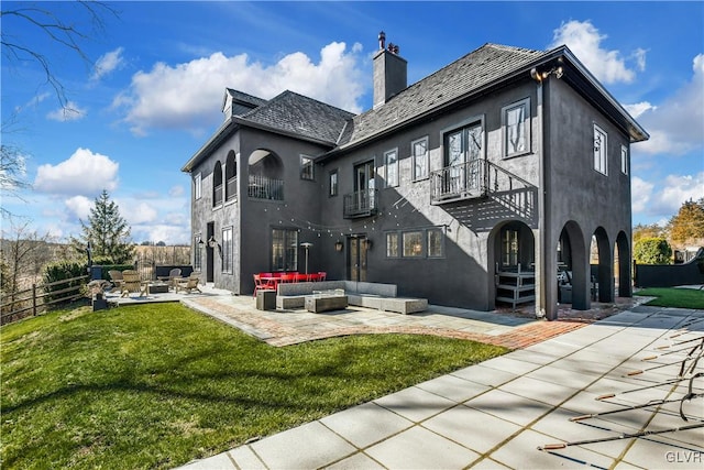 rear view of house with a patio, a balcony, an outdoor hangout area, and a lawn