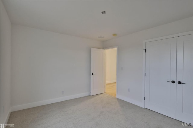 unfurnished bedroom with light carpet and a closet