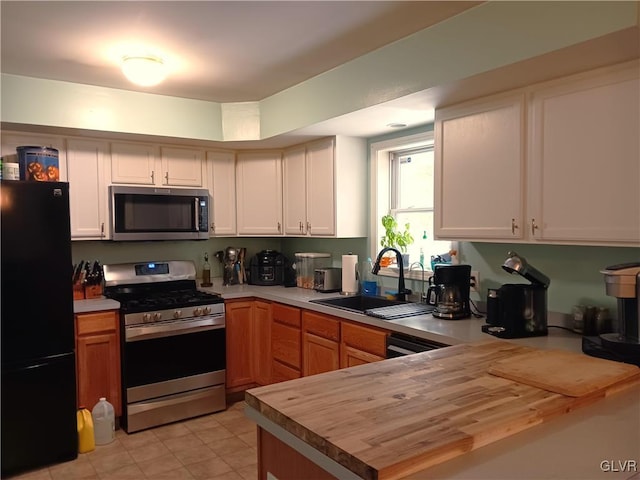 kitchen with butcher block countertops, white cabinetry, sink, and black appliances