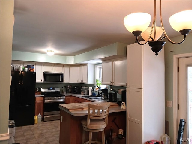 kitchen with kitchen peninsula, appliances with stainless steel finishes, sink, white cabinets, and a breakfast bar area