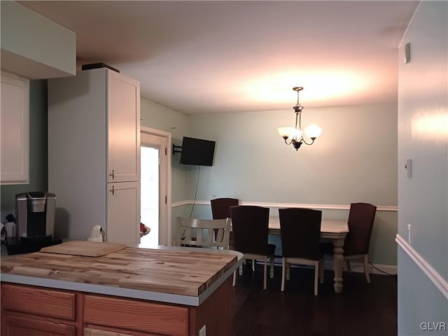 kitchen with a chandelier, pendant lighting, butcher block countertops, and white cabinetry