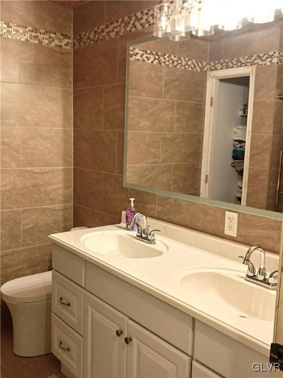 bathroom featuring vanity, tile walls, and toilet