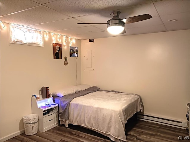 bedroom featuring a paneled ceiling, dark wood-type flooring, electric panel, a baseboard heating unit, and ceiling fan