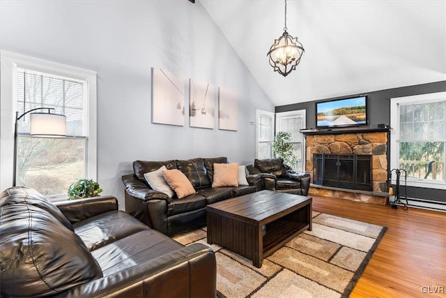 living room featuring a stone fireplace, high vaulted ceiling, wood-type flooring, and a notable chandelier