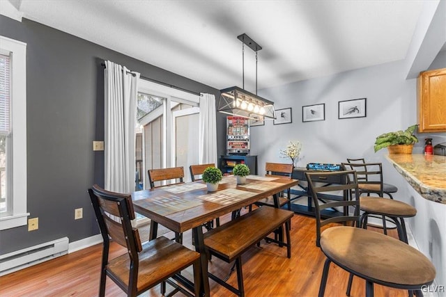 dining space featuring a chandelier, light hardwood / wood-style flooring, and a baseboard radiator