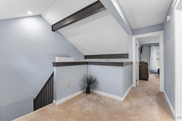 hall with lofted ceiling and light carpet