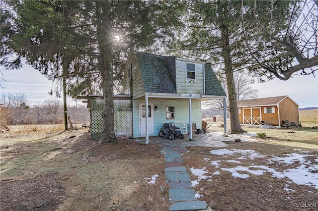 back of house with a storage unit