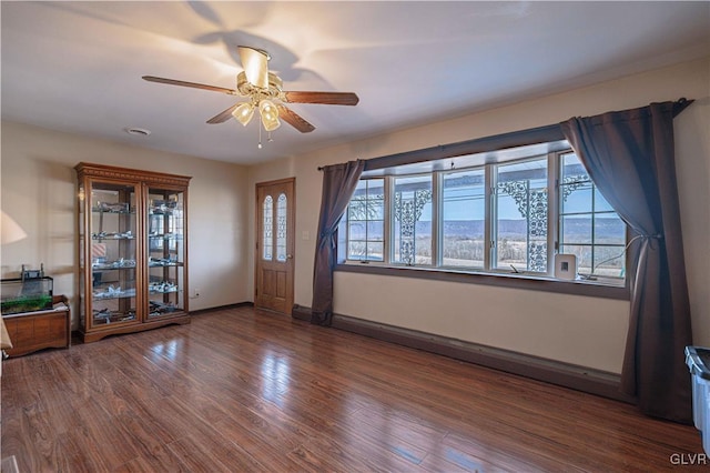 interior space with a mountain view, dark wood-type flooring, and ceiling fan