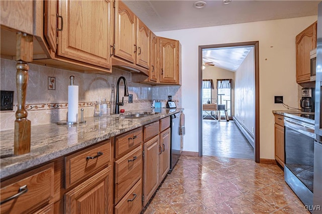 kitchen featuring appliances with stainless steel finishes, tasteful backsplash, lofted ceiling, light stone counters, and sink