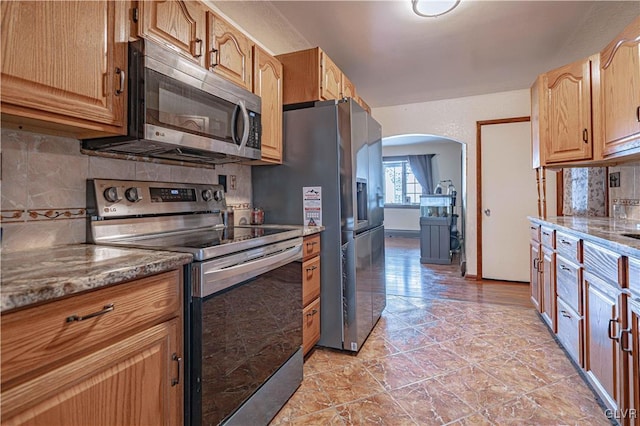 kitchen with stainless steel appliances, decorative backsplash, and light stone counters