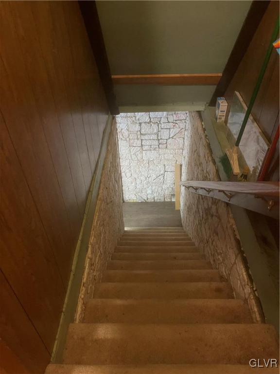 staircase featuring wooden walls