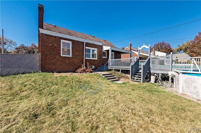 back of property featuring a pool side deck and a yard