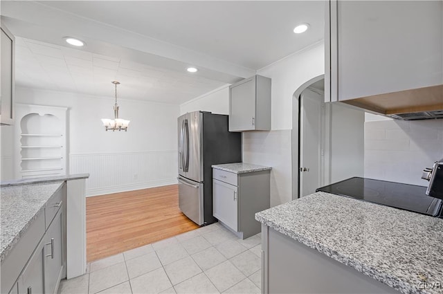 kitchen with stainless steel fridge, crown molding, light tile patterned floors, decorative light fixtures, and gray cabinets