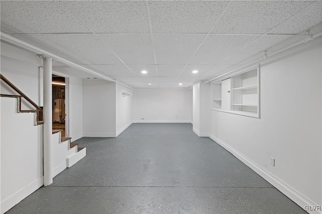 basement featuring a paneled ceiling and built in features