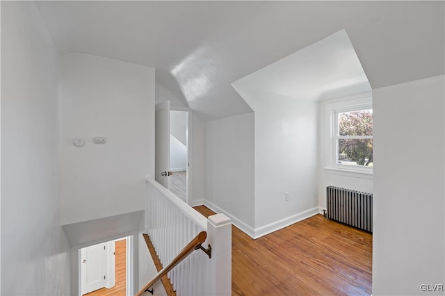 corridor featuring radiator heating unit, light hardwood / wood-style flooring, and lofted ceiling